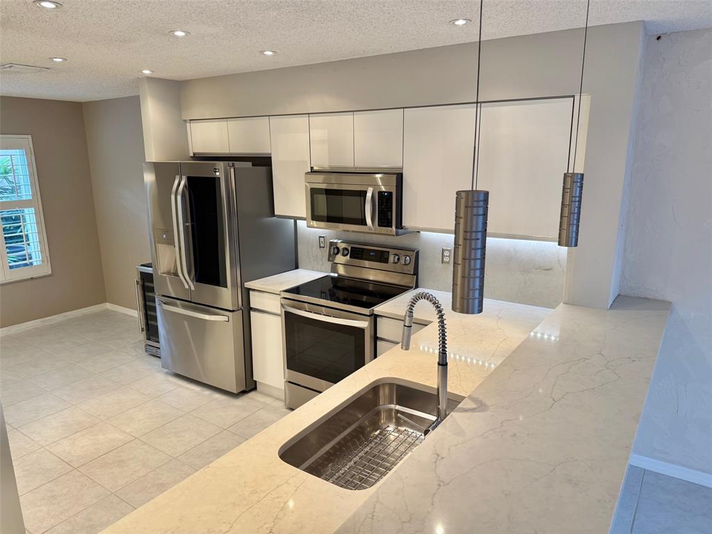 1654 Southwest 109th Terrace Davie, FL 33324 - Photo 6 of 24 a kitchen with a refrigerator a microwave a stove and a window