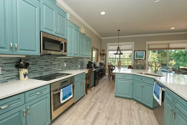 a kitchen with stainless steel appliances kitchen island granite countertop a table chairs sink and cabinets