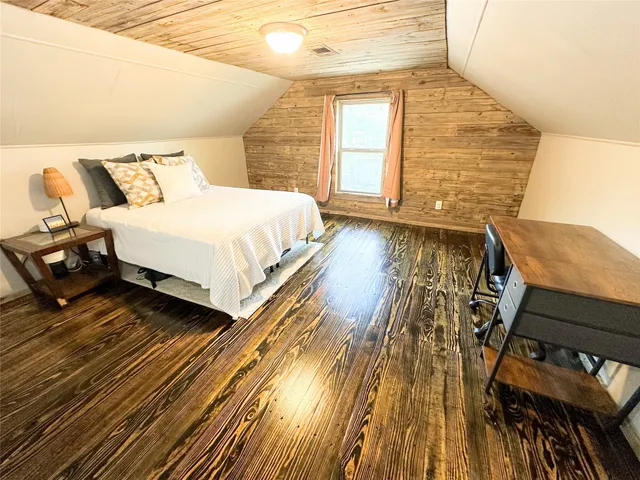 a spacious bedroom with a bed and wooden floor