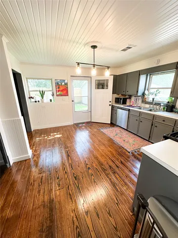 a kitchen with stainless steel appliances wooden floor and a refrigerator