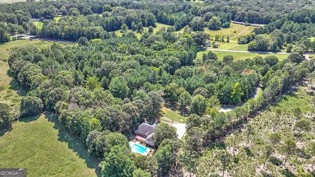 an aerial view of residential house with outdoor space and trees all around