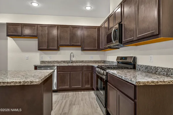 a kitchen with kitchen island granite countertop a sink stove and microwave
