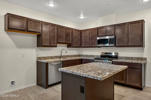 a large kitchen with stainless steel appliances granite countertop a stove top oven a sink and a refrigerator