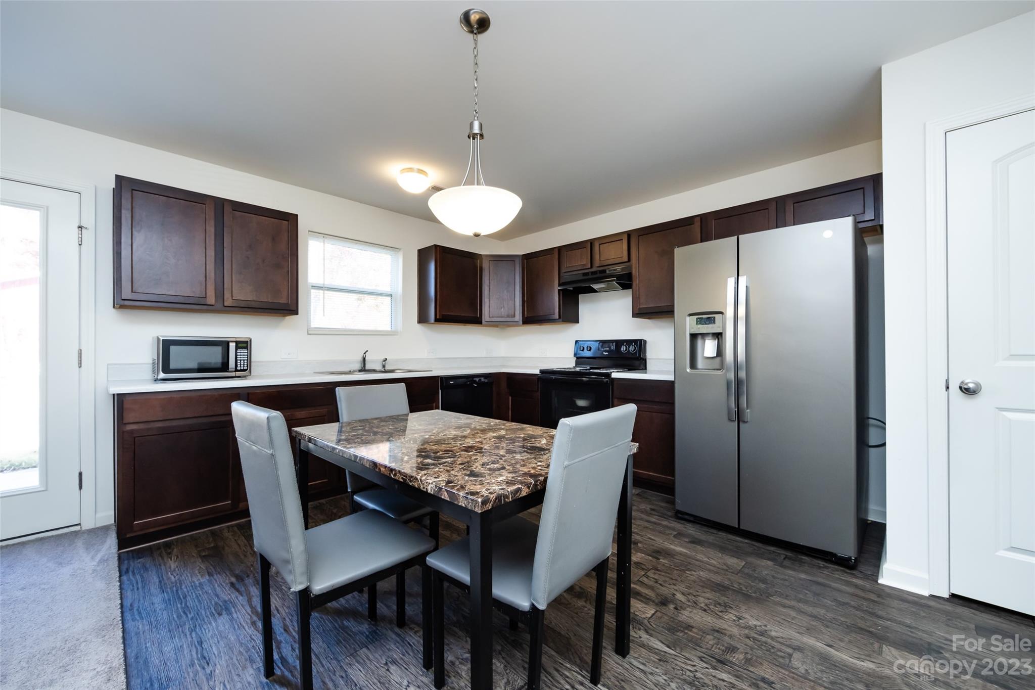 3823 Tersk Drive Midland, NC 28107 - Photo 11 of 24 a kitchen with stainless steel appliances granite countertop a dining table chairs refrigerator and microwave