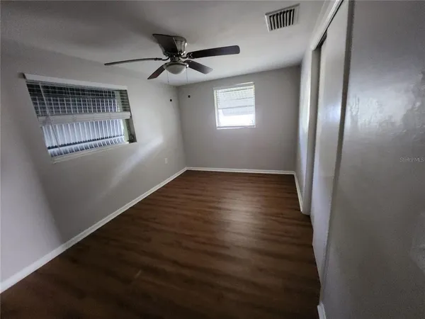 a view of an empty room with wooden floor and a window