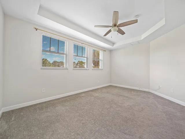 an empty room with ceiling fan and windows