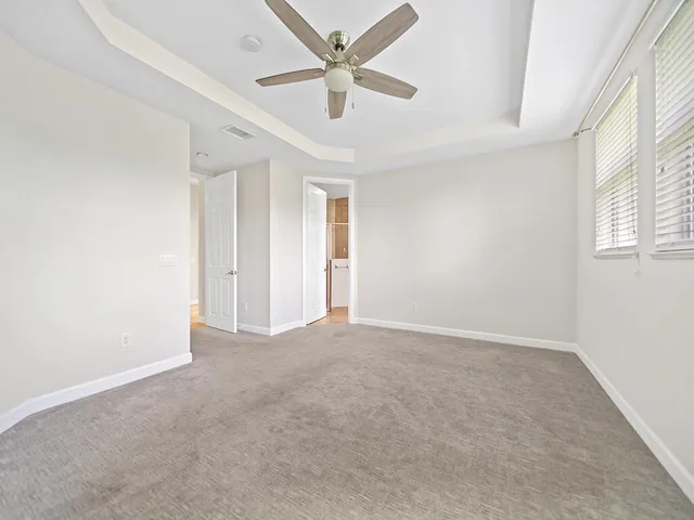 an empty room with chandelier fan and windows