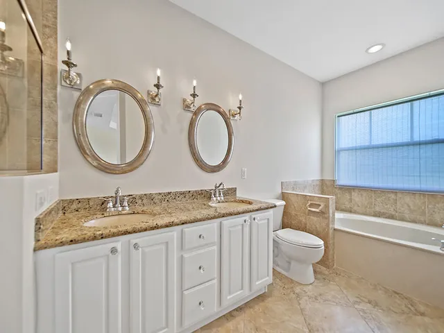 a bathroom with a granite countertop toilet a sink and a mirror