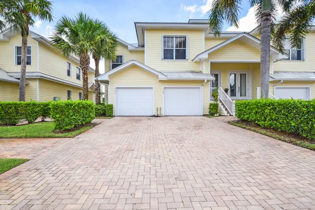 a front view of a house with a garden and palm trees