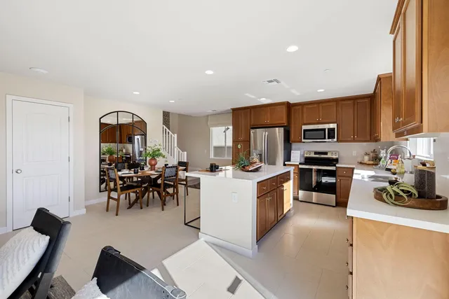 a kitchen with stainless steel appliances granite countertop a refrigerator a stove a sink a dining table and chairs with wooden floor