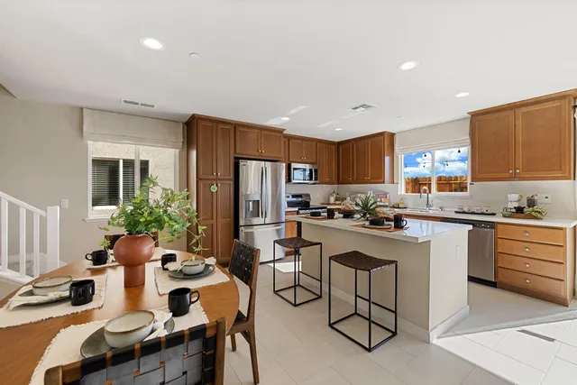 a kitchen with a refrigerator a stove a sink dishwasher with a dining table and chairs