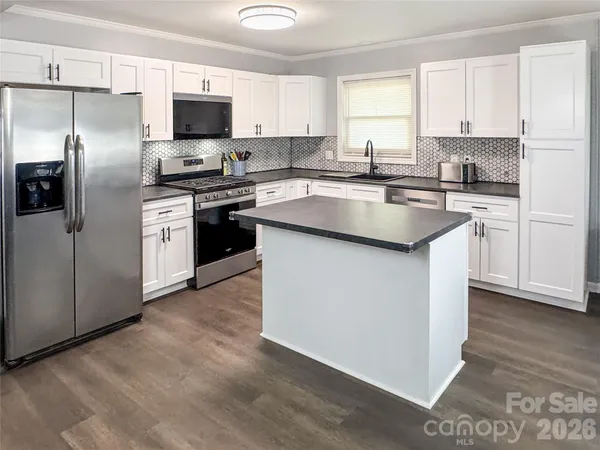 a kitchen with kitchen island a sink dishwasher a refrigerator and a stove with wooden floor