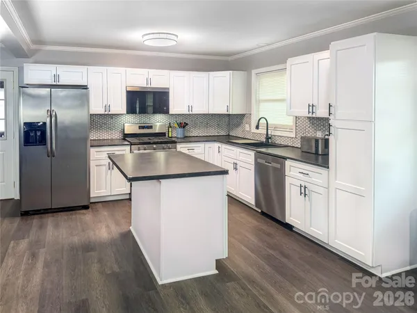 a kitchen with stainless steel appliances granite countertop a stove top oven a refrigerator a sink and dishwasher with wooden floors
