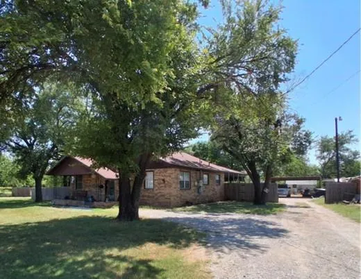 a front view of a house with a garden and trees