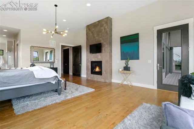 a bedroom with a large bed a flat tv screen and a fireplace