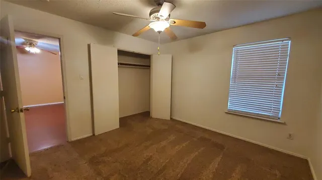 a view of empty room with window and ceiling fan