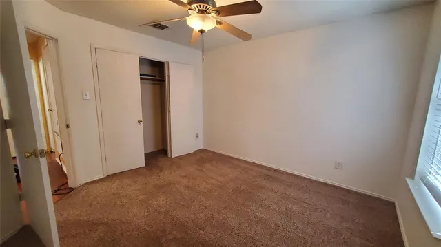 an empty room with a fan and a window