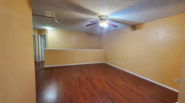 an empty room with wooden floor chandelier fan and closet area