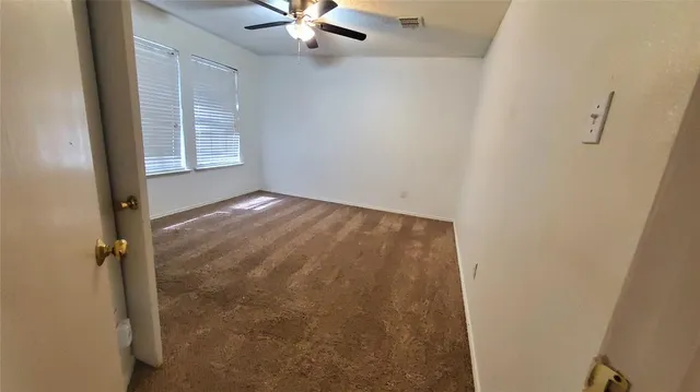 an empty room with windows and fan