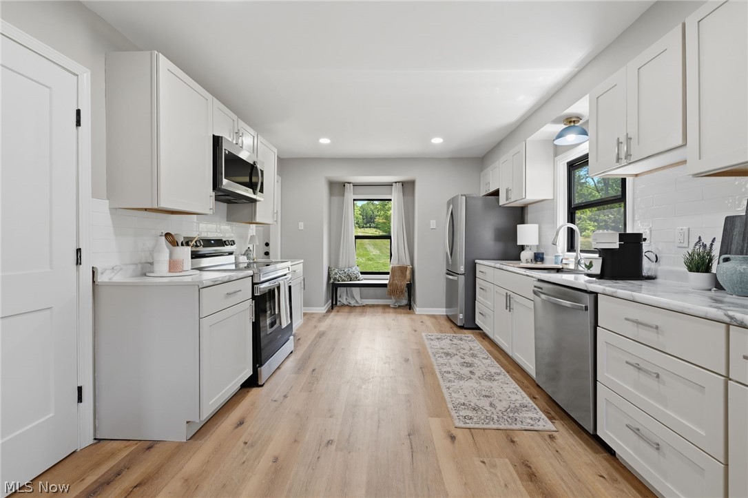 951 Bey Road Akron, OH 44312 - Photo 12 of 34 Kitchen featuring wood-finish flooring, white cabinetry, stainless steel appliances, and light-toned countertops with a white subway tile backsplash