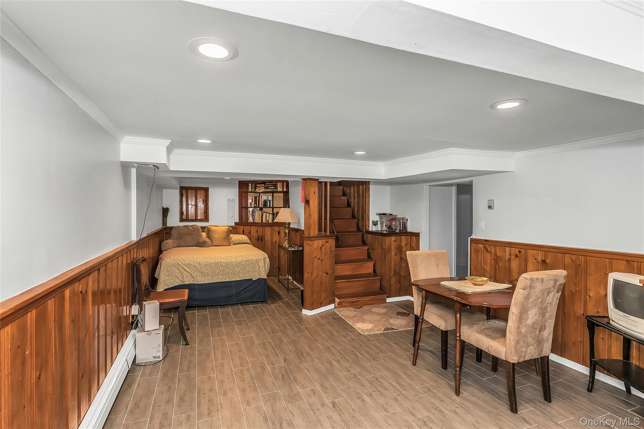 622 Wellelein Road Uniondale, NY 11553 - Photo 13 of 18 Bedroom featuring a wainscoted wall, wooden walls, ornamental molding, wood finish floors, and a baseboard heating unit