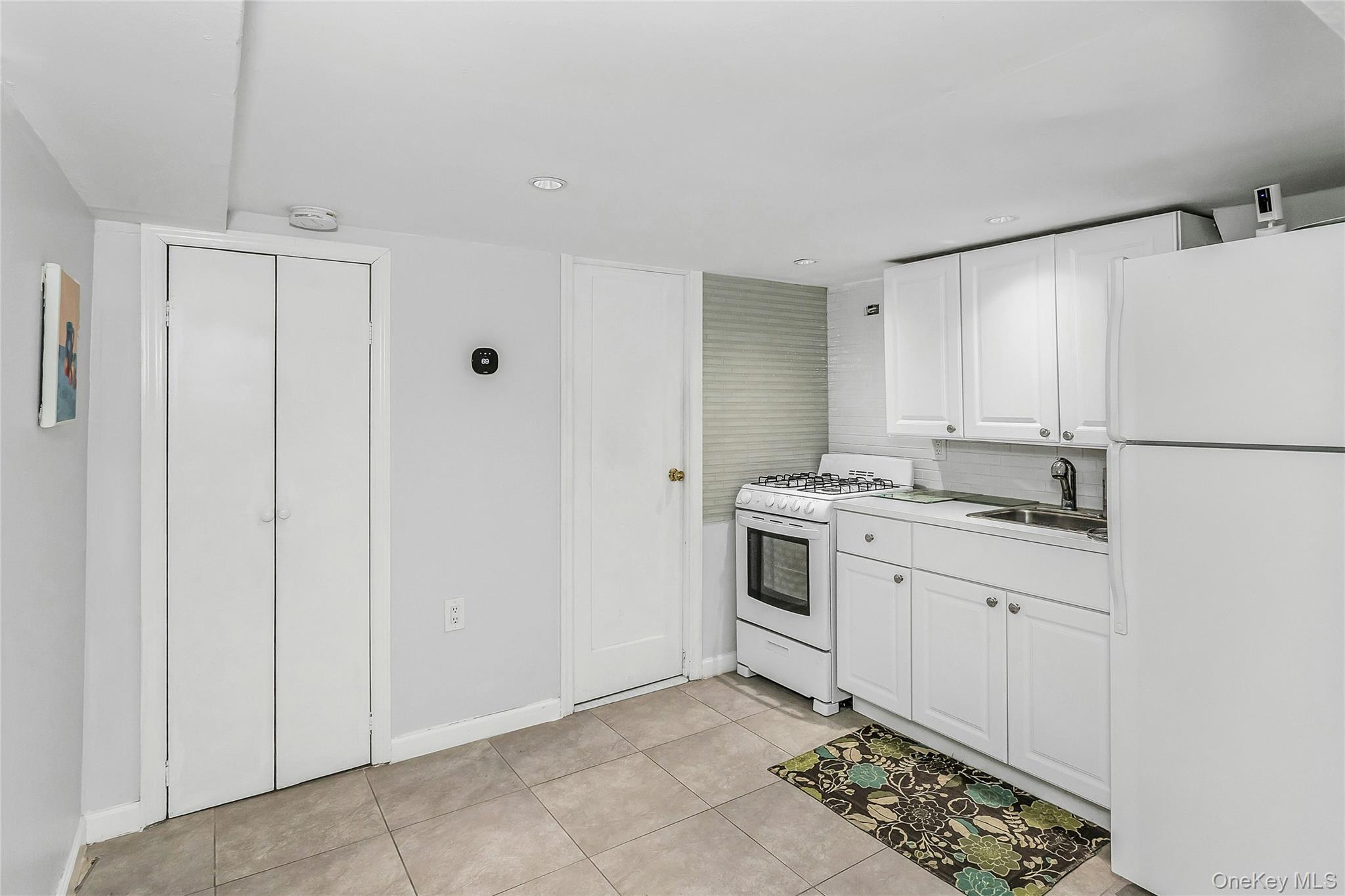 622 Wellelein Road Uniondale, NY 11553 - Photo 14 of 18 Kitchen featuring white appliances, white cabinetry, light countertops, light tile patterned flooring, and recessed lighting