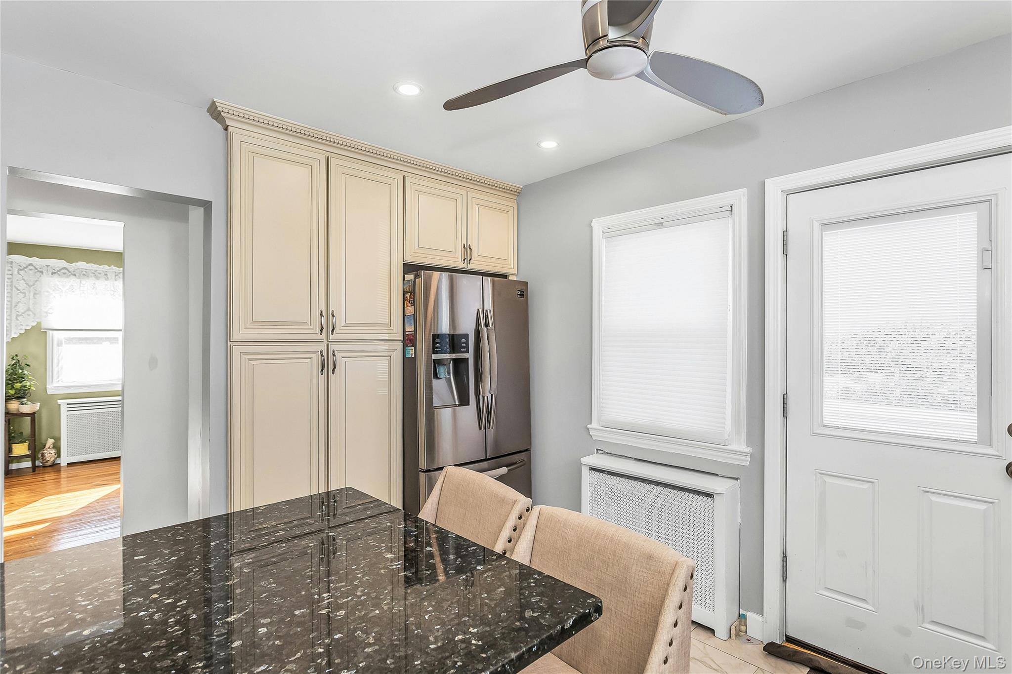 622 Wellelein Road Uniondale, NY 11553 - Photo 6 of 18 Kitchen featuring cream cabinetry, stainless steel refrigerator with ice dispenser, radiator heating unit, ceiling fan, and recessed lighting