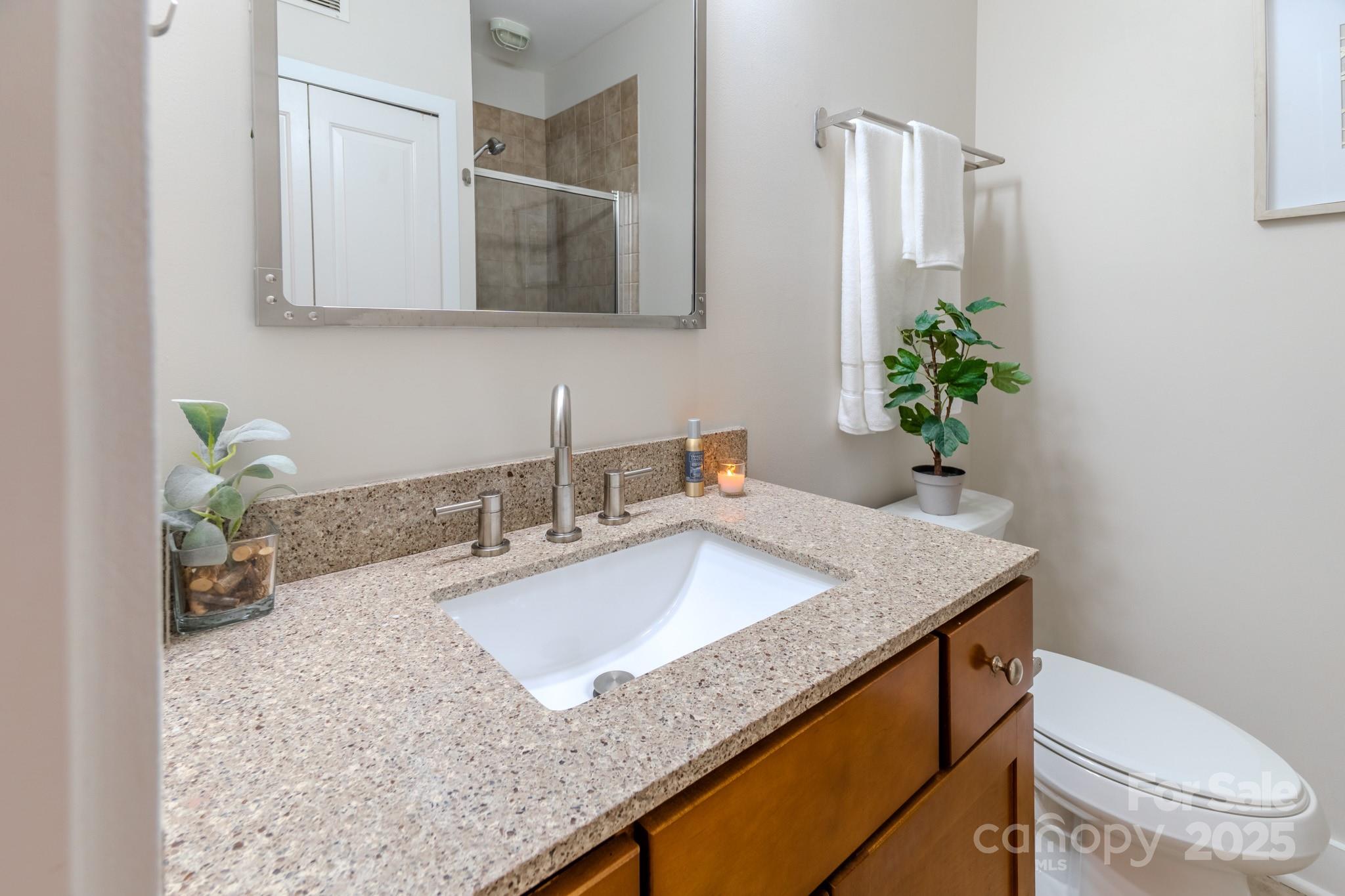 630 Calvert Street, Unit 1110 Charlotte, NC 28208 - Photo 20 of 28 a bathroom with a granite countertop sink a toilet and mirror