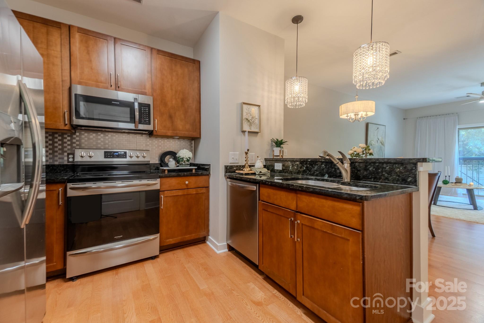 630 Calvert Street, Unit 1110 Charlotte, NC 28208 - Photo 9 of 28 a kitchen with stainless steel appliances granite countertop a sink a stove a microwave and wooden cabinets