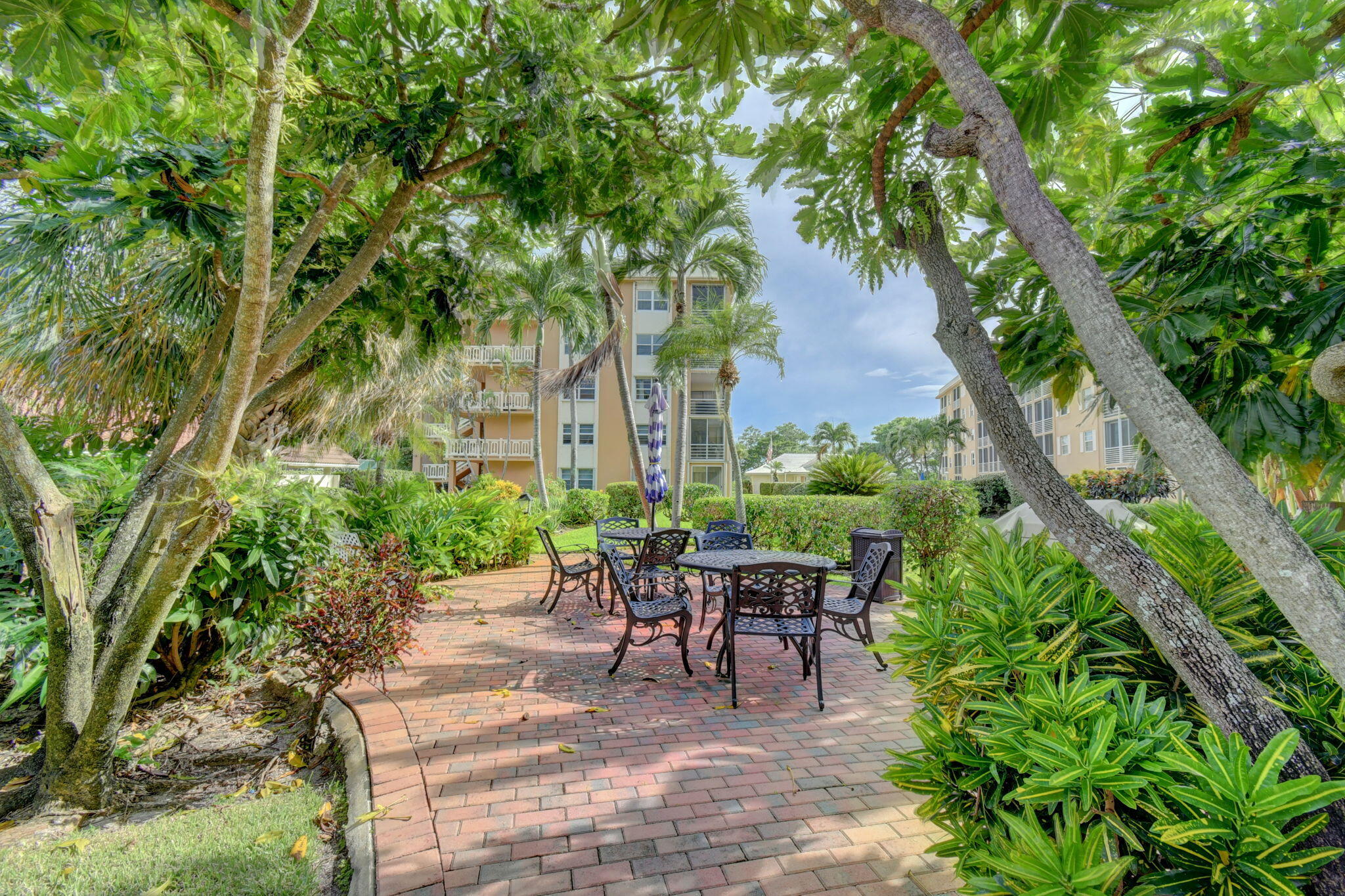 300 Golfview Road, Unit 407 North Palm Beach, FL 33408 - Photo 33 of 56 a view of a patio with table and chairs potted plants and large tree