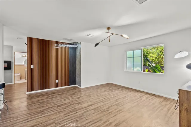 a view of an empty room with window and wooden floor