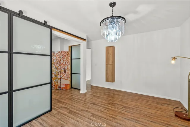 a view of empty room with wooden floor and kitchen view
