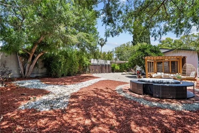 a view of a backyard with table and chairs plants and large tree