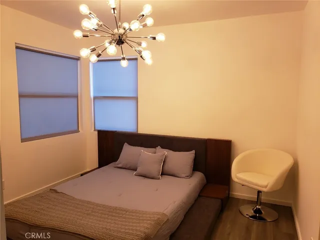 a bedroom with a bed chandelier and a window