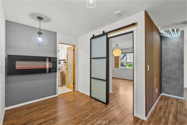 a view of a hallway with wooden floor and a refrigerator