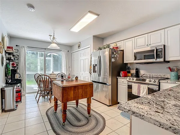 a kitchen with stainless steel appliances granite countertop a stove top oven a sink a refrigerator white cabinets and wooden floor