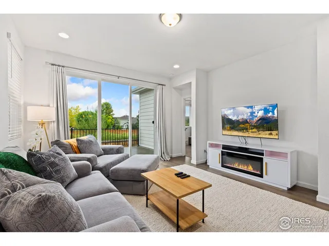 a living room with furniture a flat screen tv and a large window