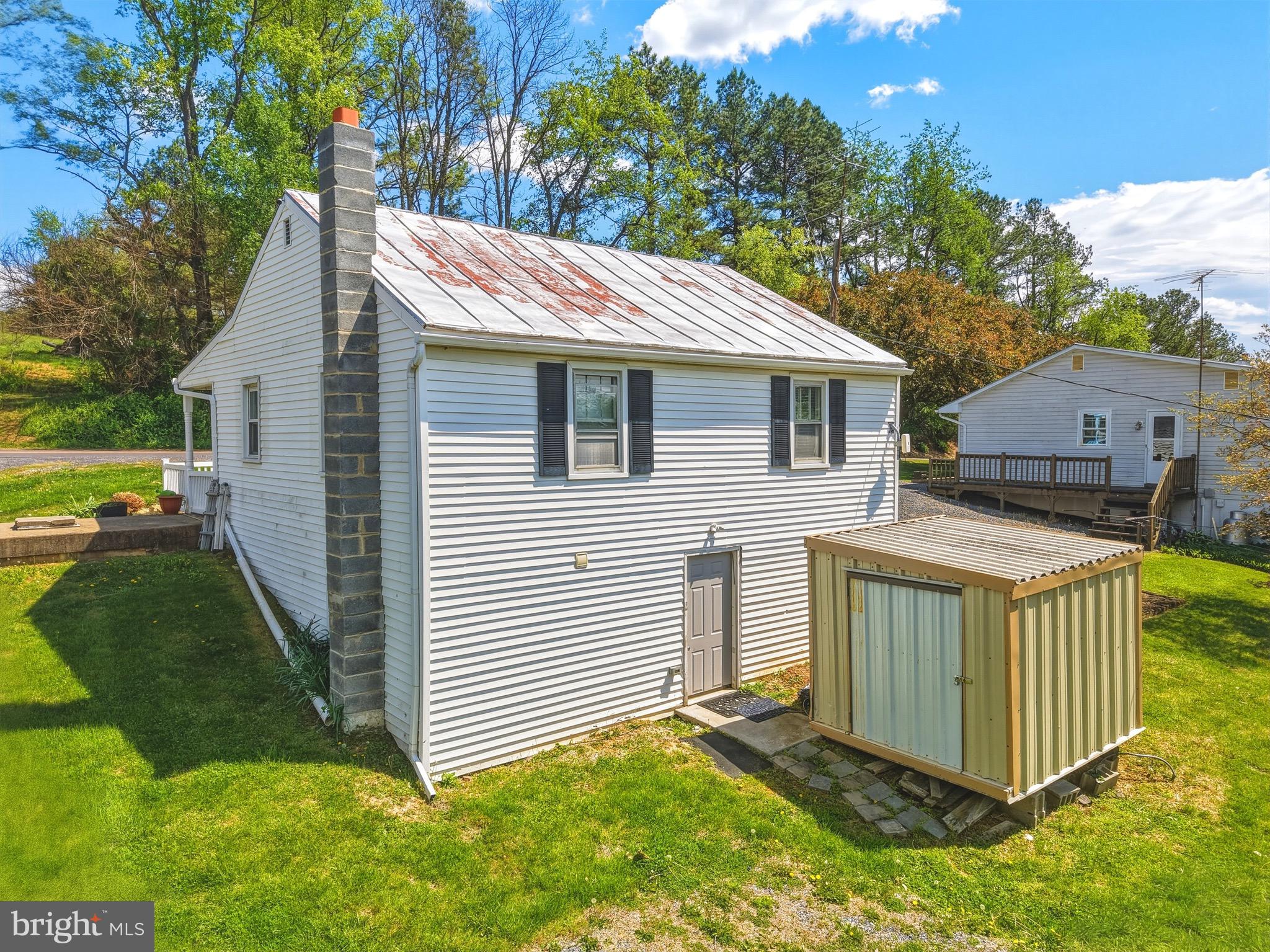 353 Turkey Knob Road Quicksburg, VA 22847 - Photo 23 of 35 a view of a house with a yard and lawn chairs under an umbrella