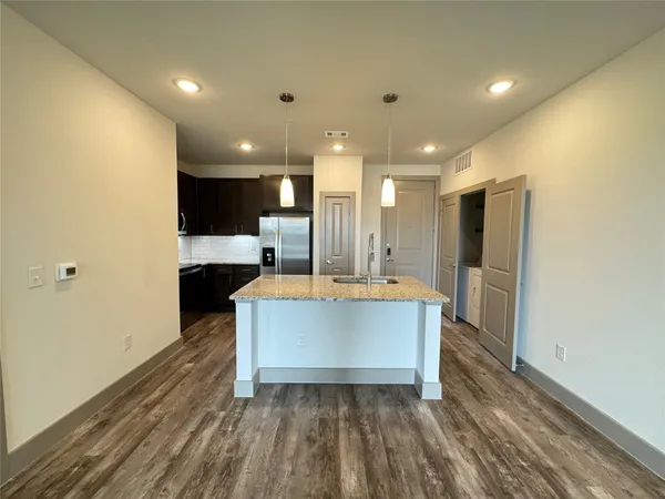 a large kitchen with stainless steel appliances a large counter top a refrigerator and a sink