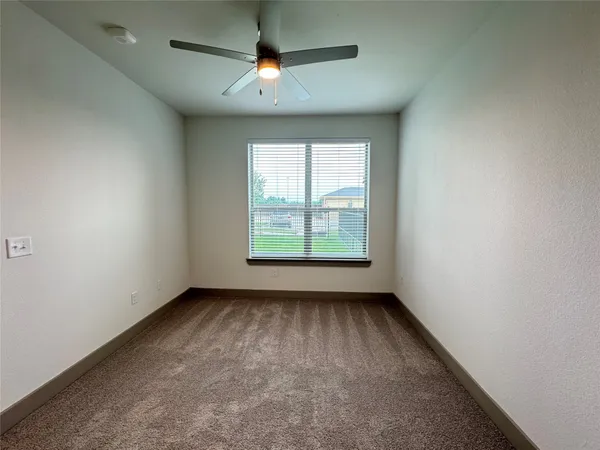 an empty room with a window and a fan