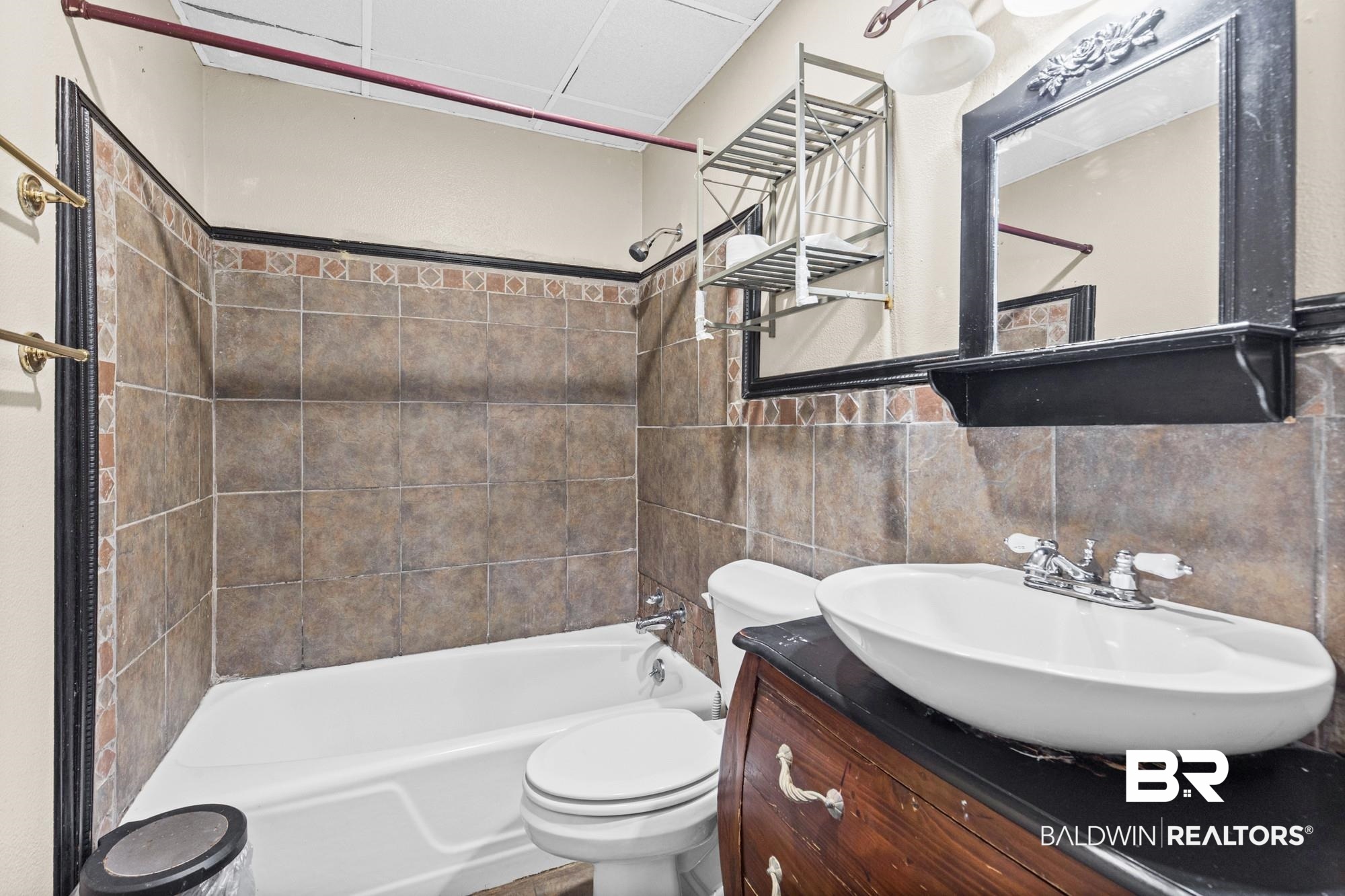 5510 Richmond Road Mobile, AL 36608 - Photo 12 of 21 Bathroom featuring a white bathtub, ceramic tile surround, and a wood-finish vanity with a vessel sink