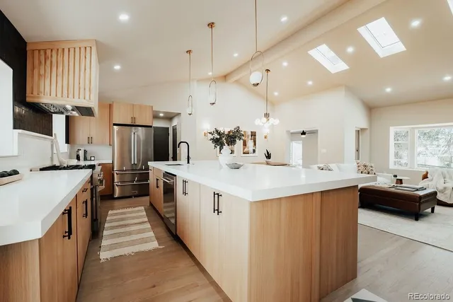 a kitchen with stainless steel appliances kitchen island granite countertop a sink and a refrigerator