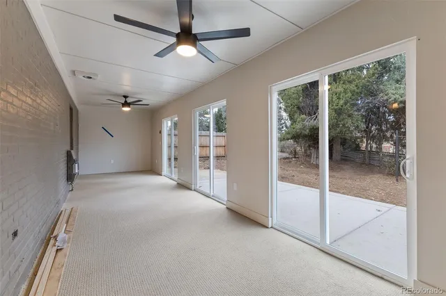a view of a big room with large windows and a ceiling fan