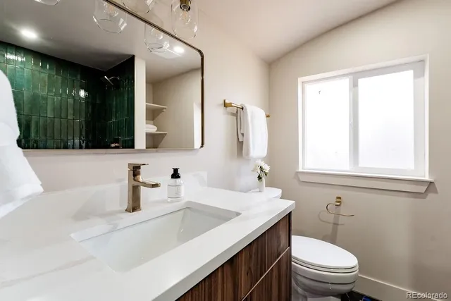 a bathroom with a sink a toilet a mirror and window