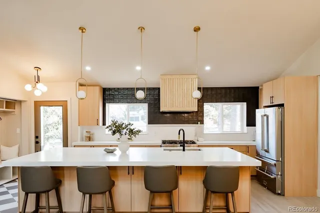 a kitchen with stainless steel appliances a sink a stove a refrigerator with a dining table and chairs