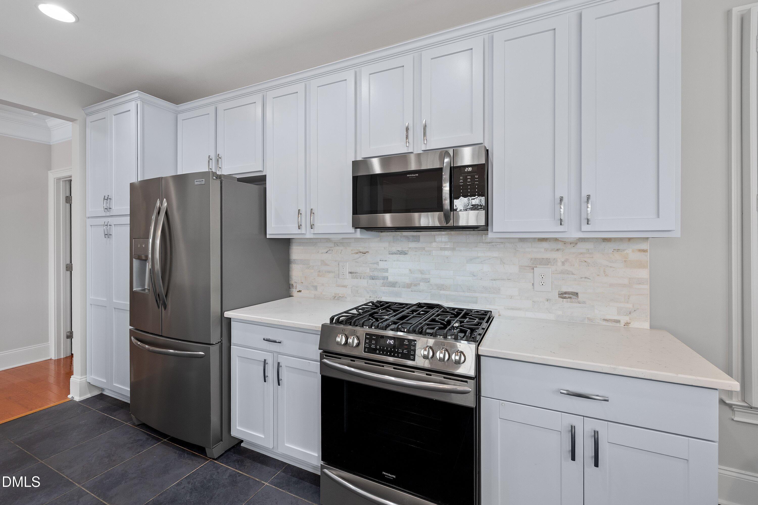 9211 Calabria Drive, Unit 205 Raleigh, NC 27617 - Photo 25 of 55 a kitchen with stainless steel appliances white cabinets white stove a microwave and a refrigerator