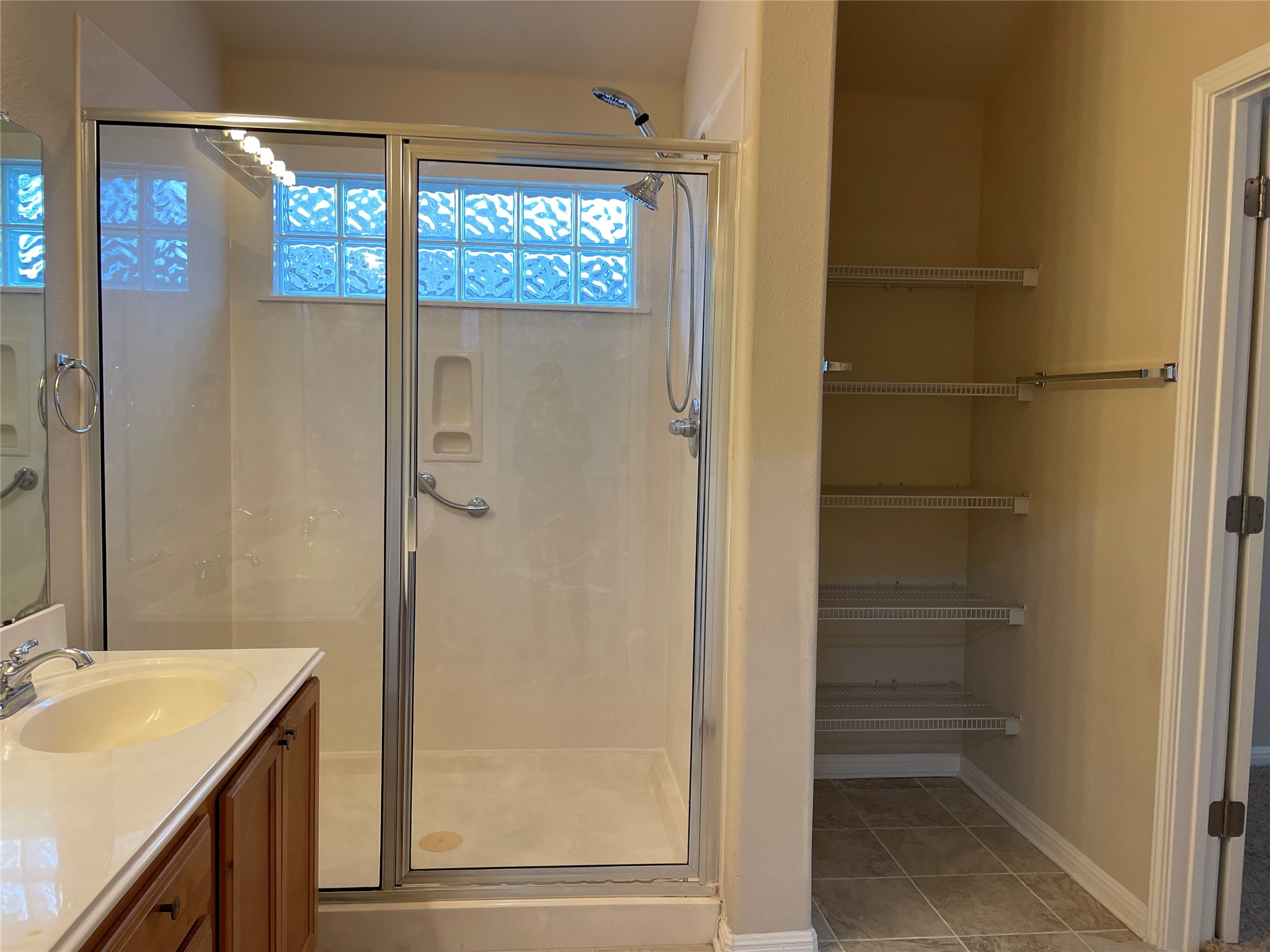 11713 Dunblane Way Austin, TX 78754 - Photo 13 of 22 Glass-enclosed shower with a block glass window, complemented by a vanity with a white countertop and wood-finish cabinetry
