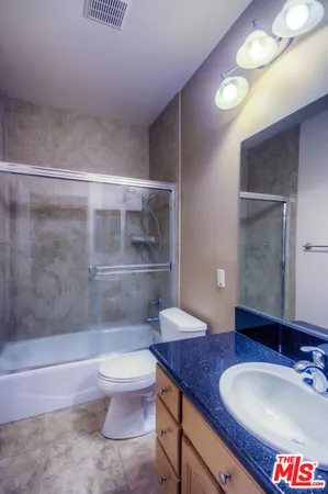 a bathroom with a granite countertop sink a toilet a mirror and shower