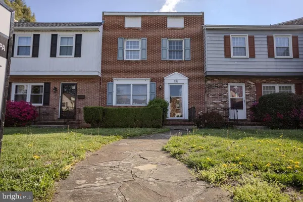 a view of a brick house with windows yard and a large tree