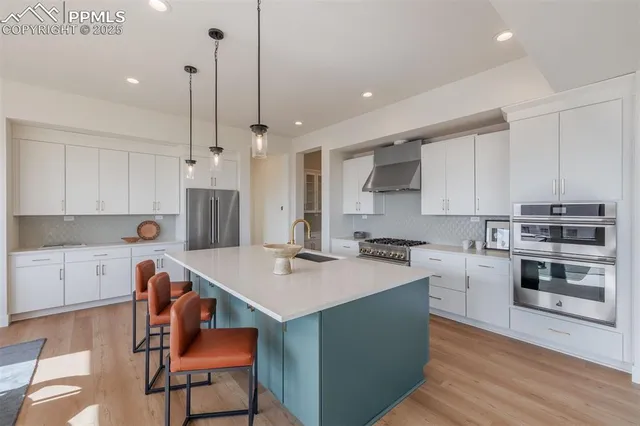 a kitchen with a stove a sink a kitchen island with chairs and wooden cabinets